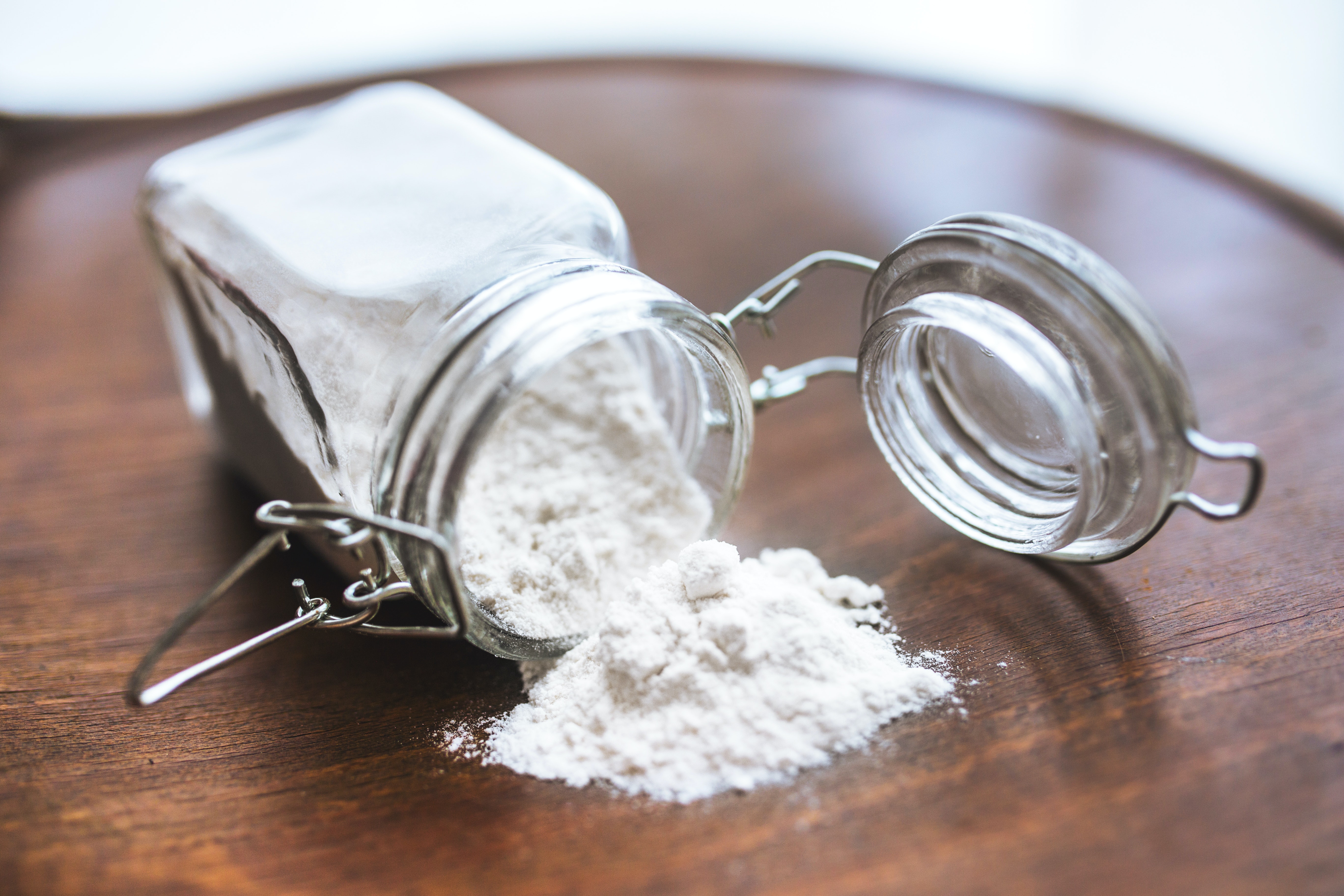 Maltodextrin White powder spilling out of a container on a wooden table