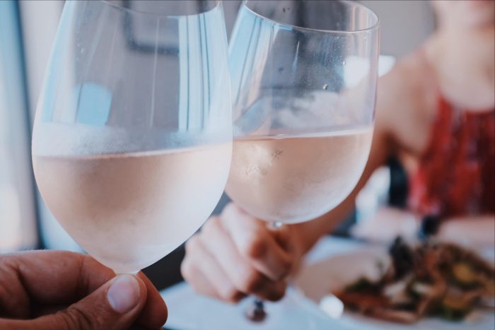 Two friends toasting with glasses of rose wine