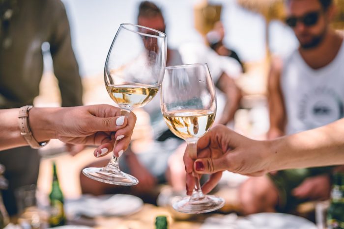 Two friends toasting with glasses of white wine at a party